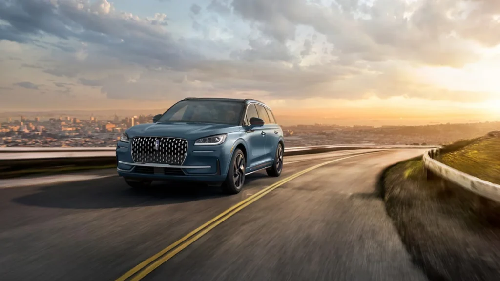 A 2025 Lincoln Corsair® Grand Touring driving on a scenic road in Cleveland at sunset.