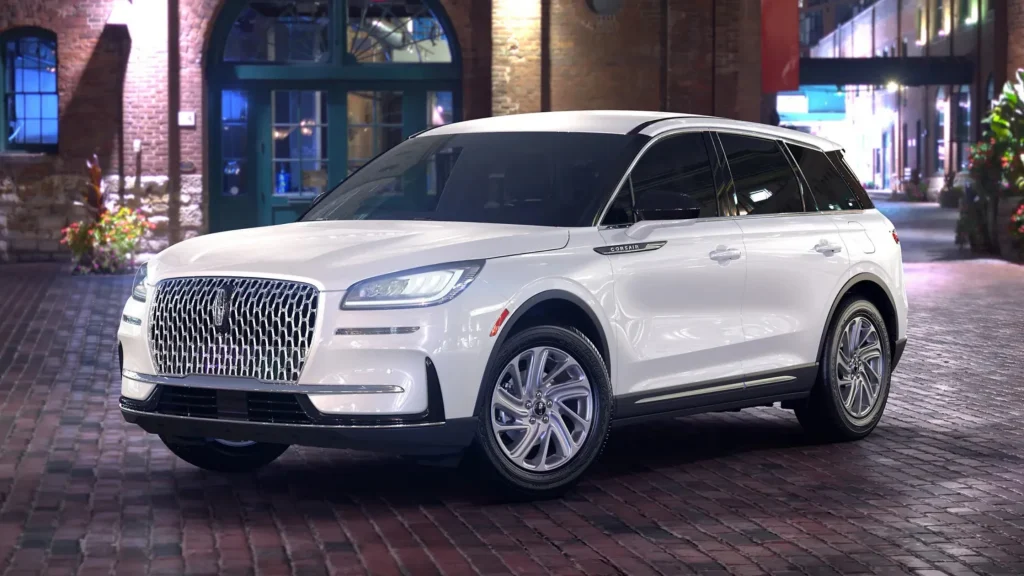 Night view of 2025 Lincoln Corsair® Premiere in white parked on brick street under city lights.