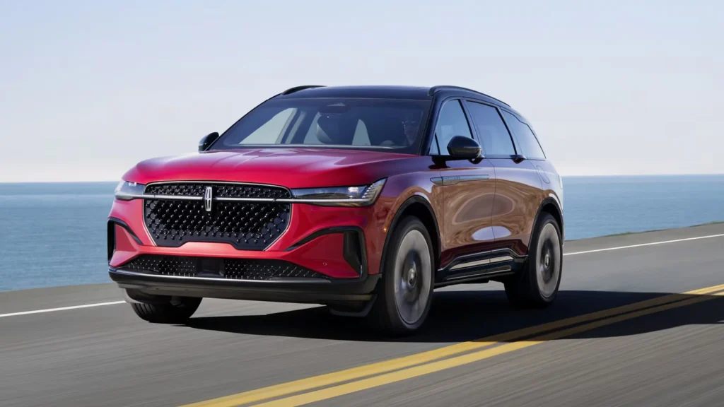 Red 2025 Lincoln Nautilus® Reserve driving on coastal road showing grille and headlights.