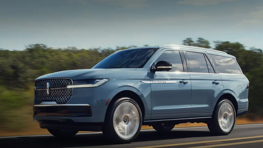 2025 Navigator Reserve SUV in blue driving with chrome grille and luxury three-row design.