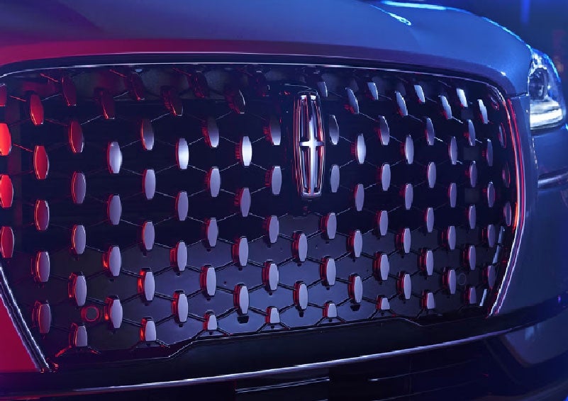 The grille of a 2025 Lincoln Corsair® SUV reflects neon light at night. | Nick Mayer Lincoln Westlake in Westlake OH