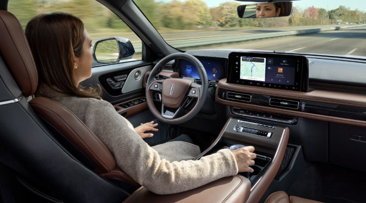 A 2026 Lincoln Aviator® SUV is being driven hands-free on a highway near a forest | Nick Mayer Lincoln Westlake in Westlake OH
