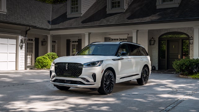 A white 2026 Lincoln Aviator® SUV is parked in the driveway of a luxury home. | Nick Mayer Lincoln Westlake in Westlake OH