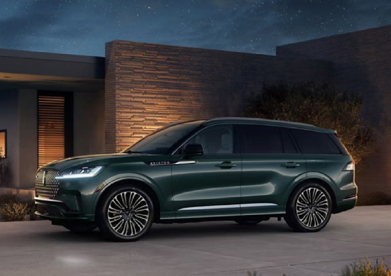 A green 2027 Lincoln Aviator® SUV is parked outside a contemporary home. | Nick Mayer Lincoln Westlake in Westlake OH