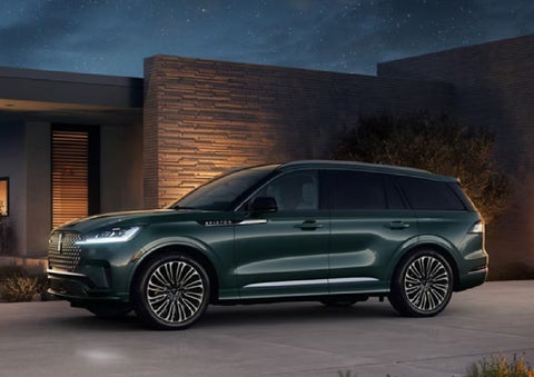 A green 2027 Lincoln Aviator® SUV is parked outside a contemporary home. | Nick Mayer Lincoln Westlake in Westlake OH