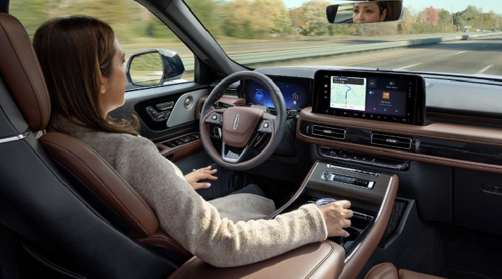 A 2027 Lincoln Aviator® SUV is being driven hands-free on a highway lined with trees. | Nick Mayer Lincoln Westlake in Westlake OH