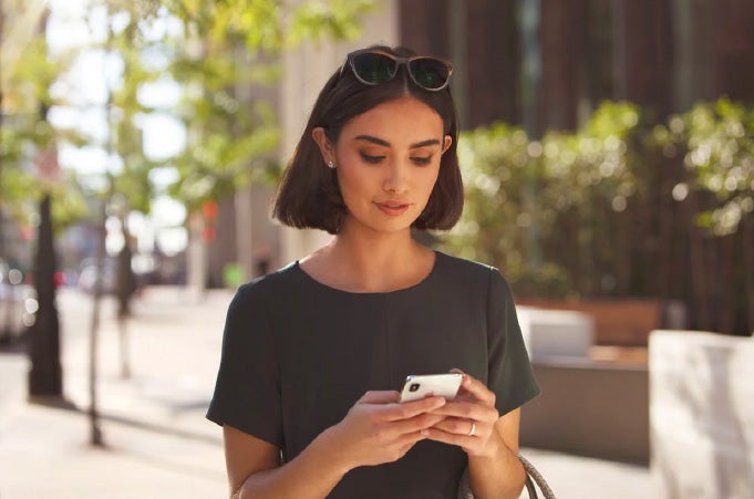 Woman holding phone outside building