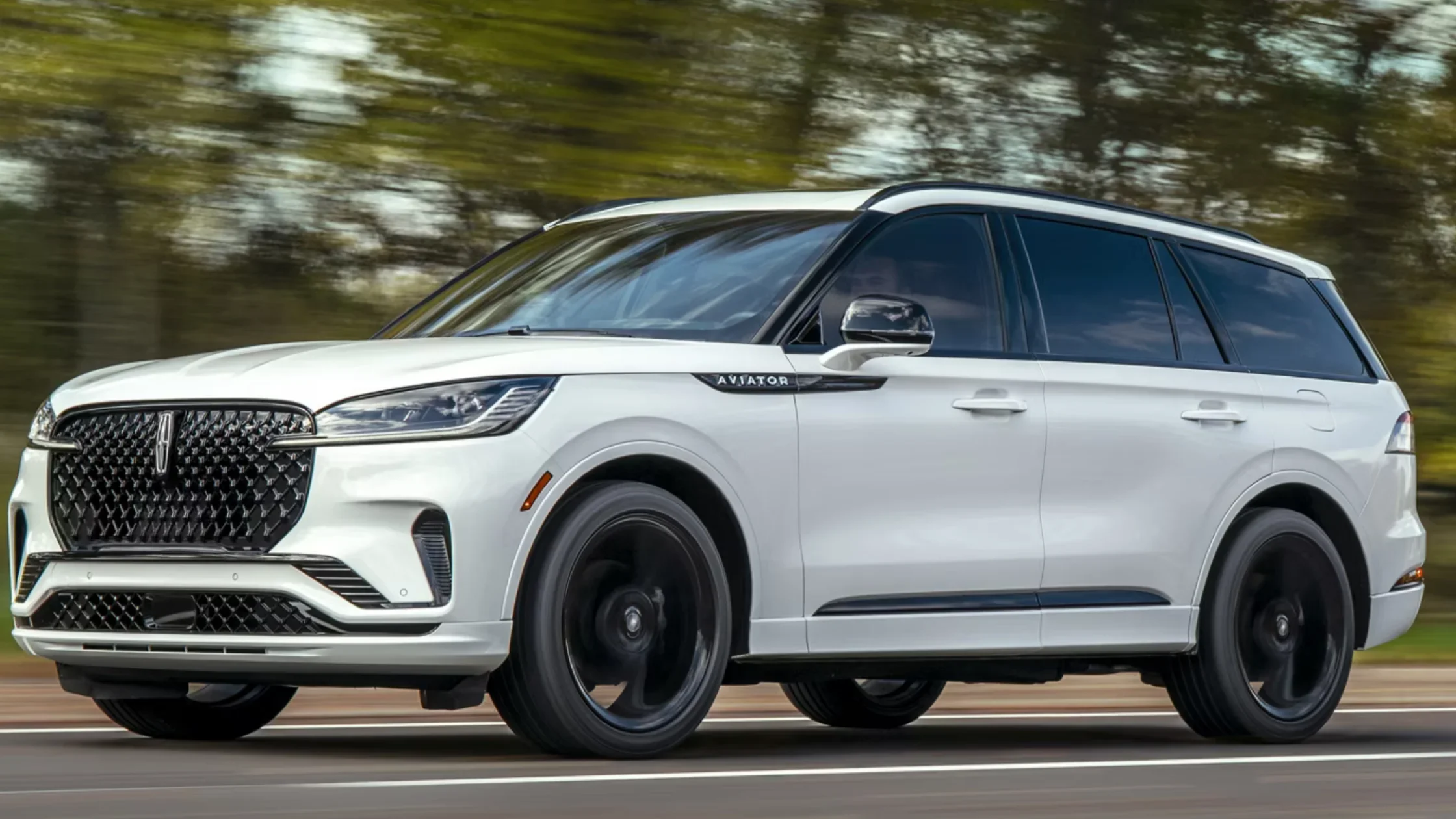 2025 Aviator® Reserve exterior in white, captured in motion with black grille, sleek headlights, and alloy wheels.