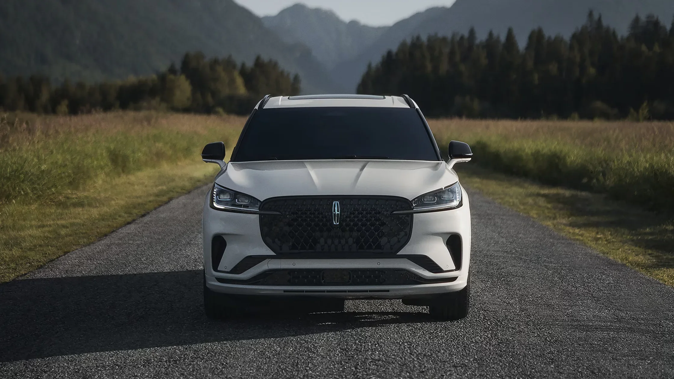 Front view of 2025 Lincoln Aviator parked on mountain road with scenic background and black mesh grille.