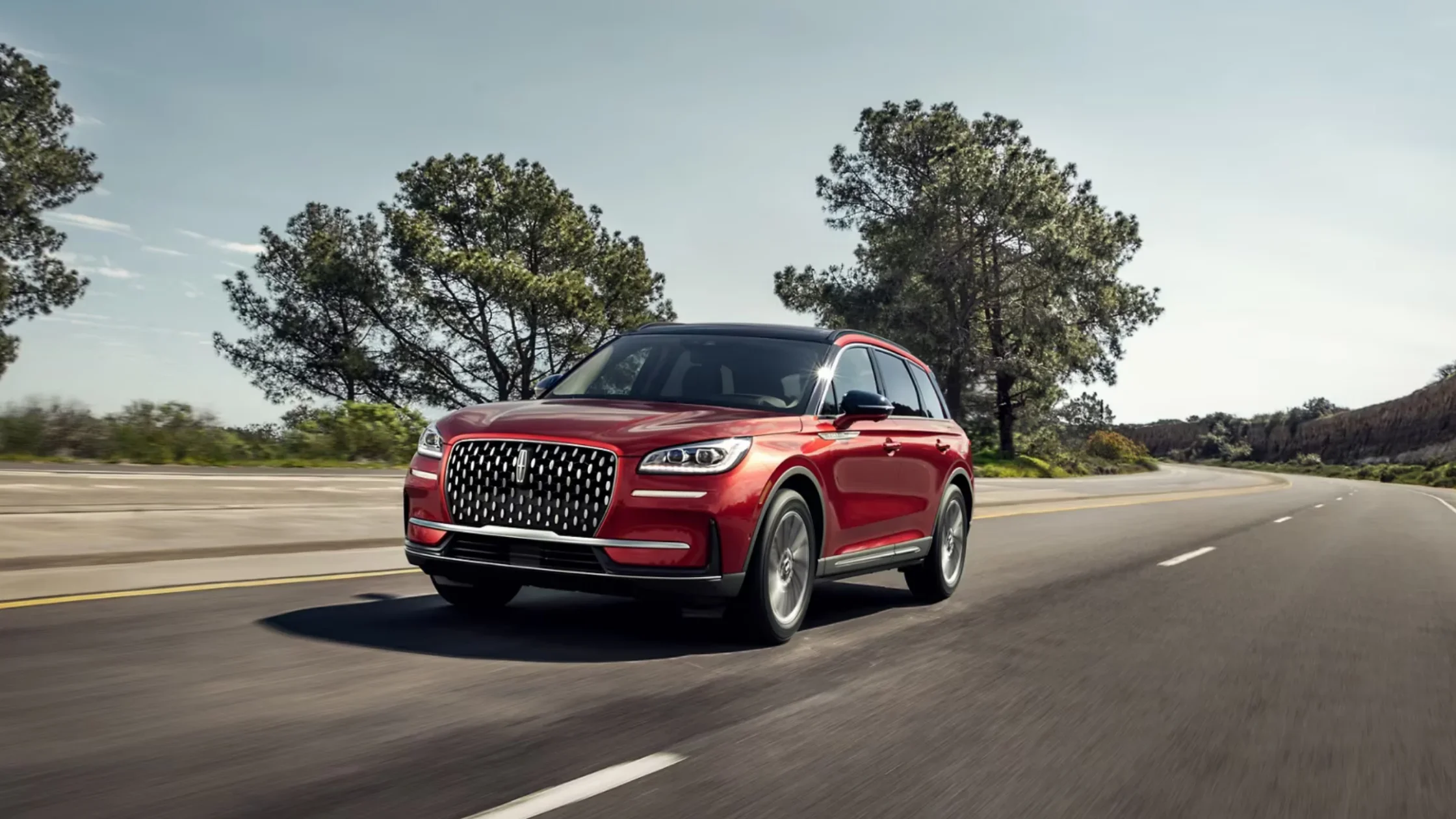 2025 Corsair® Reserve in red exterior driving on highway, bold grille, LED headlights, and sleek aerodynamic design.