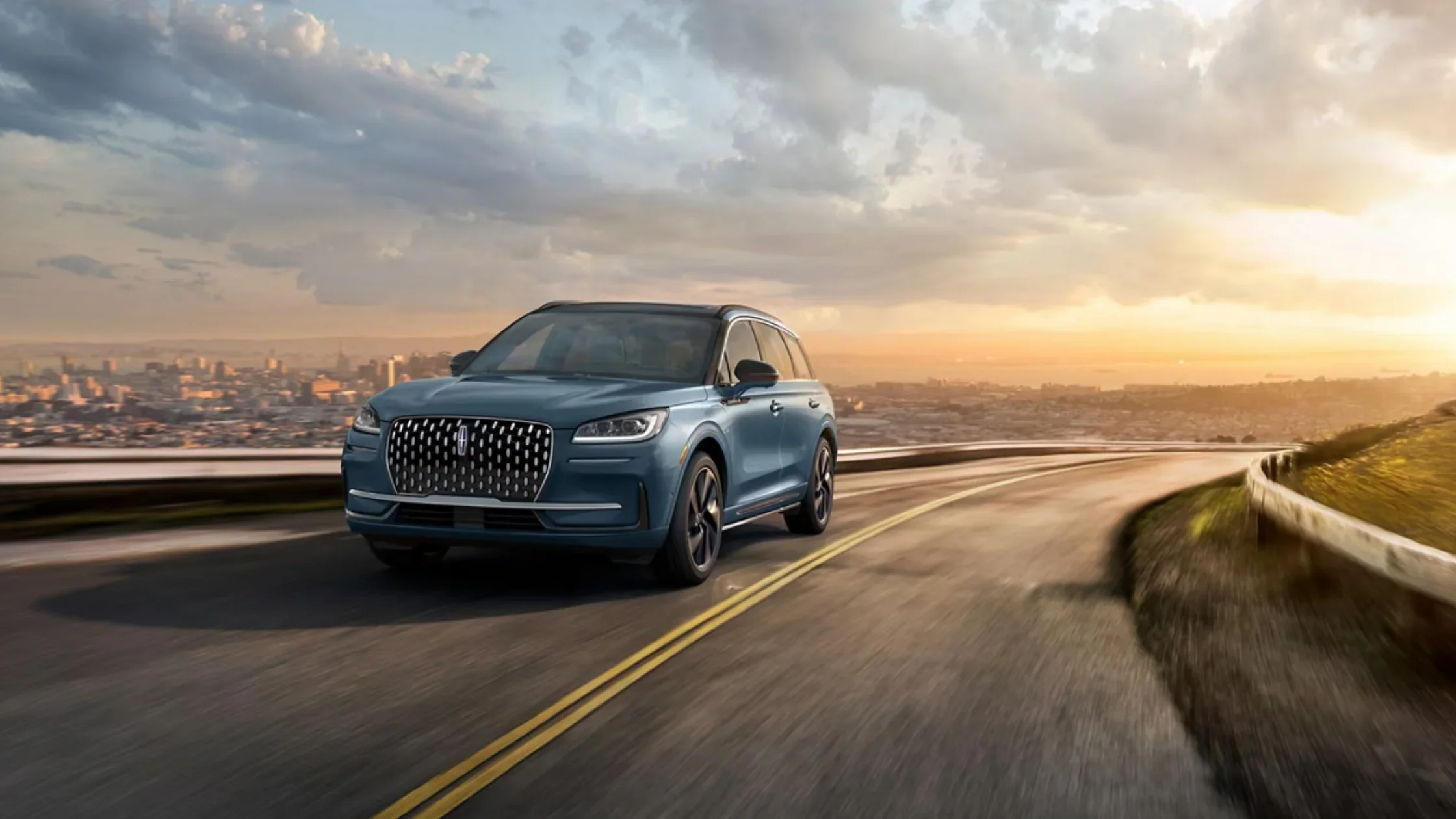 A 2025 Lincoln Corsair® Grand Touring driving on a winding road at sunset.