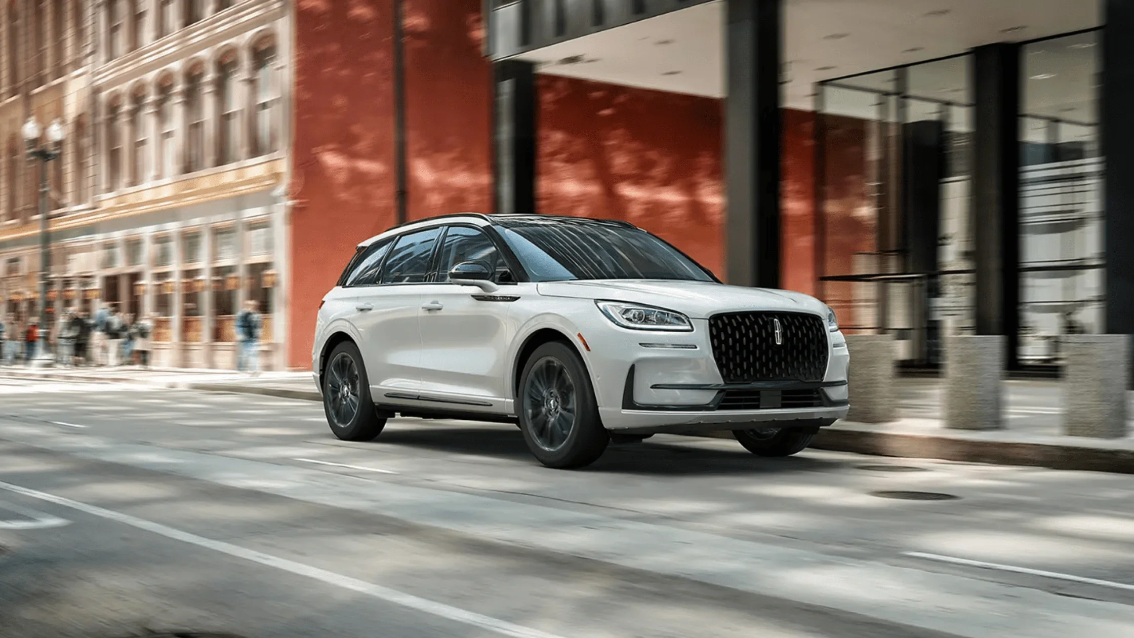 2025 Lincoln Corsair® in motion through downtown city street with red building in background