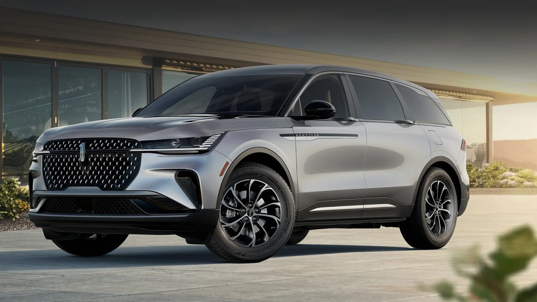 The 2025 Nautilus® Premiere parked in front of a modern home, showcasing its sleek design and bold front grille.