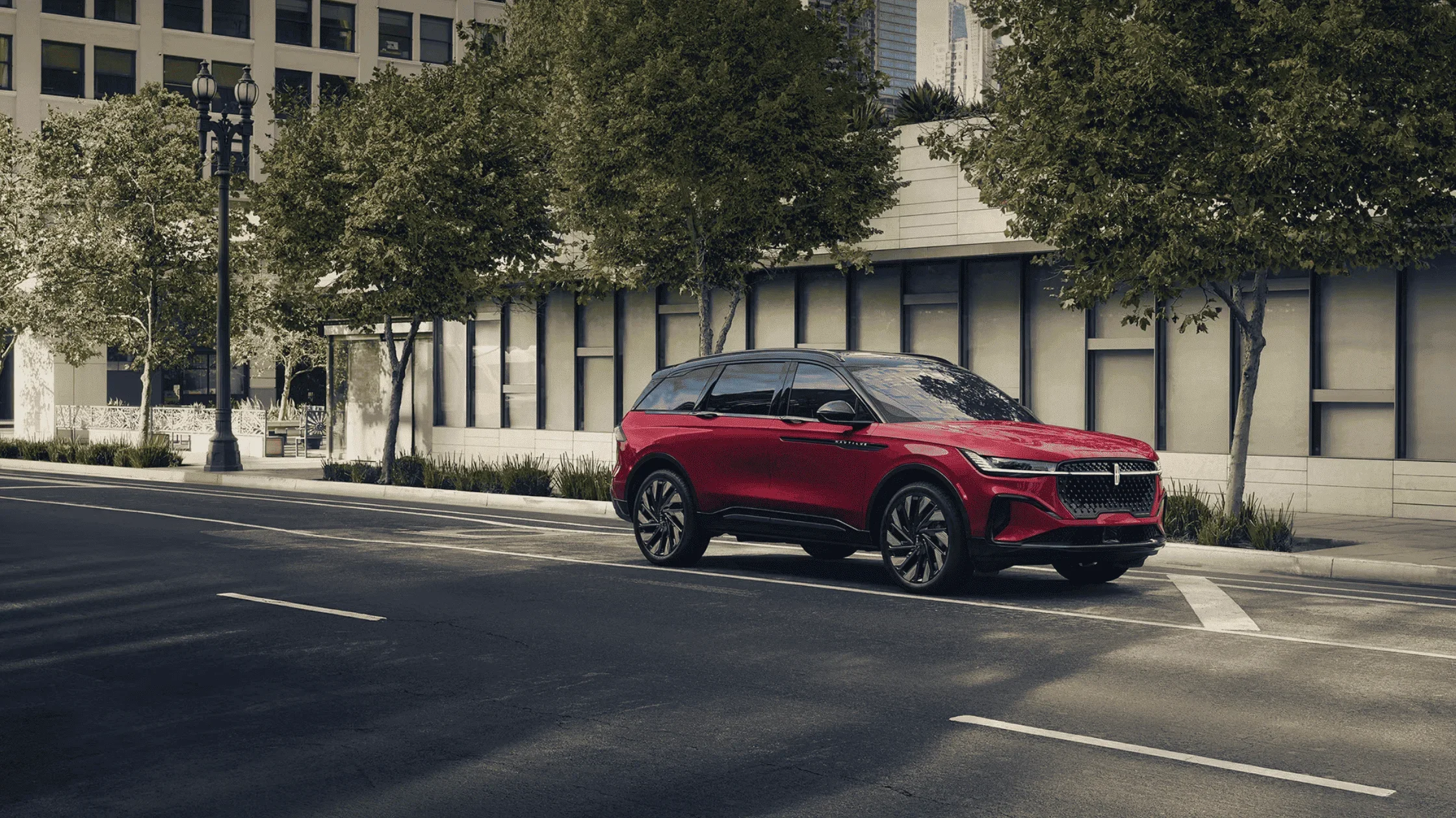 2025 Lincoln Nautilus in red parked on downtown street with modern buildings and trees