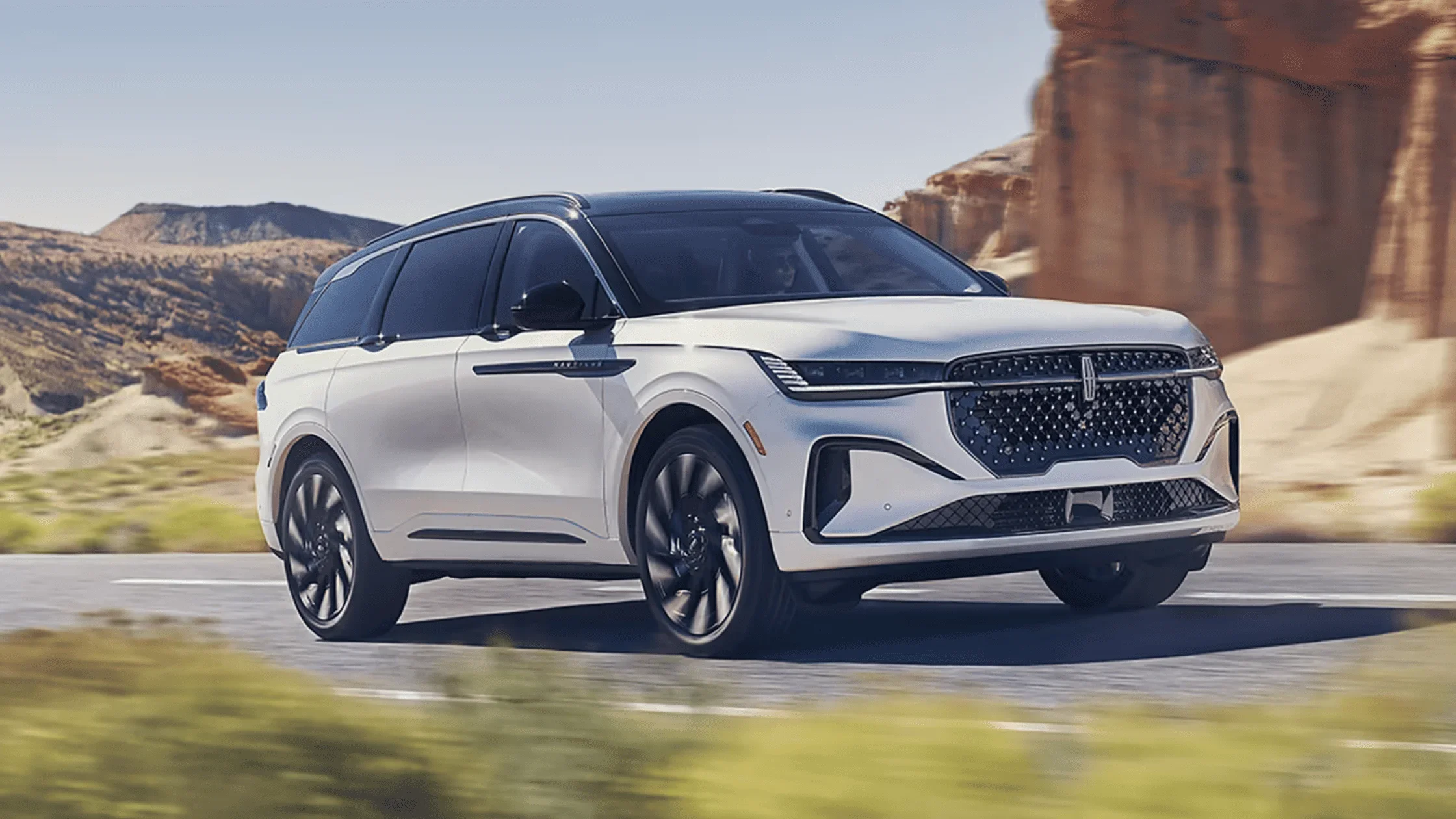 2025 Lincoln Nautilus in white driving on highway near red rock formations and blue sky