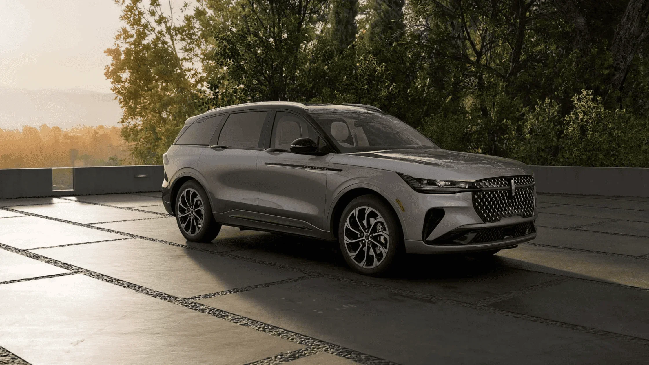 2025 Lincoln Nautilus in silver parked on concrete patio with trees and sunset in background