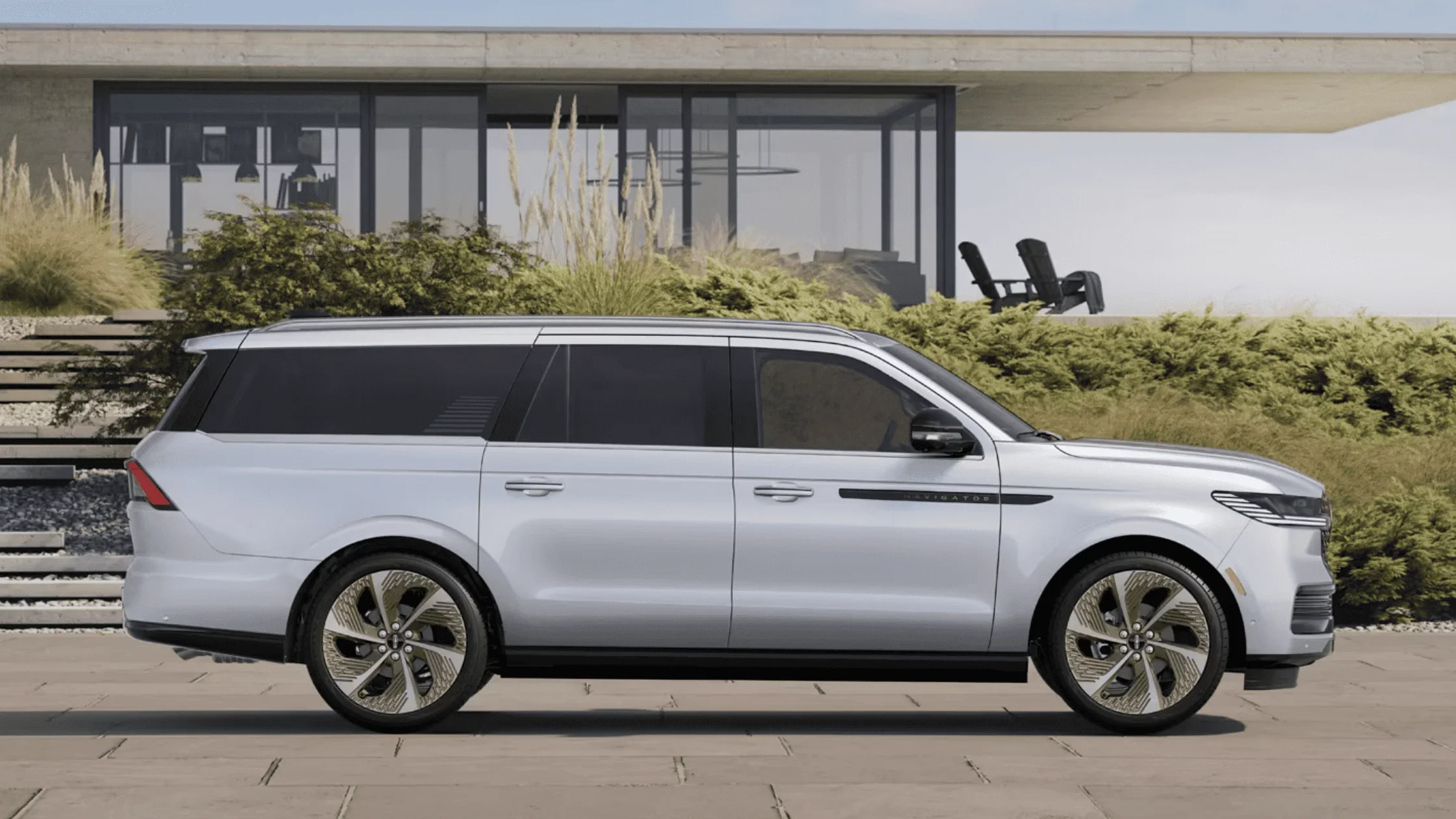 Side view of white 2025 Lincoln Navigator parked near modern home and landscaping
