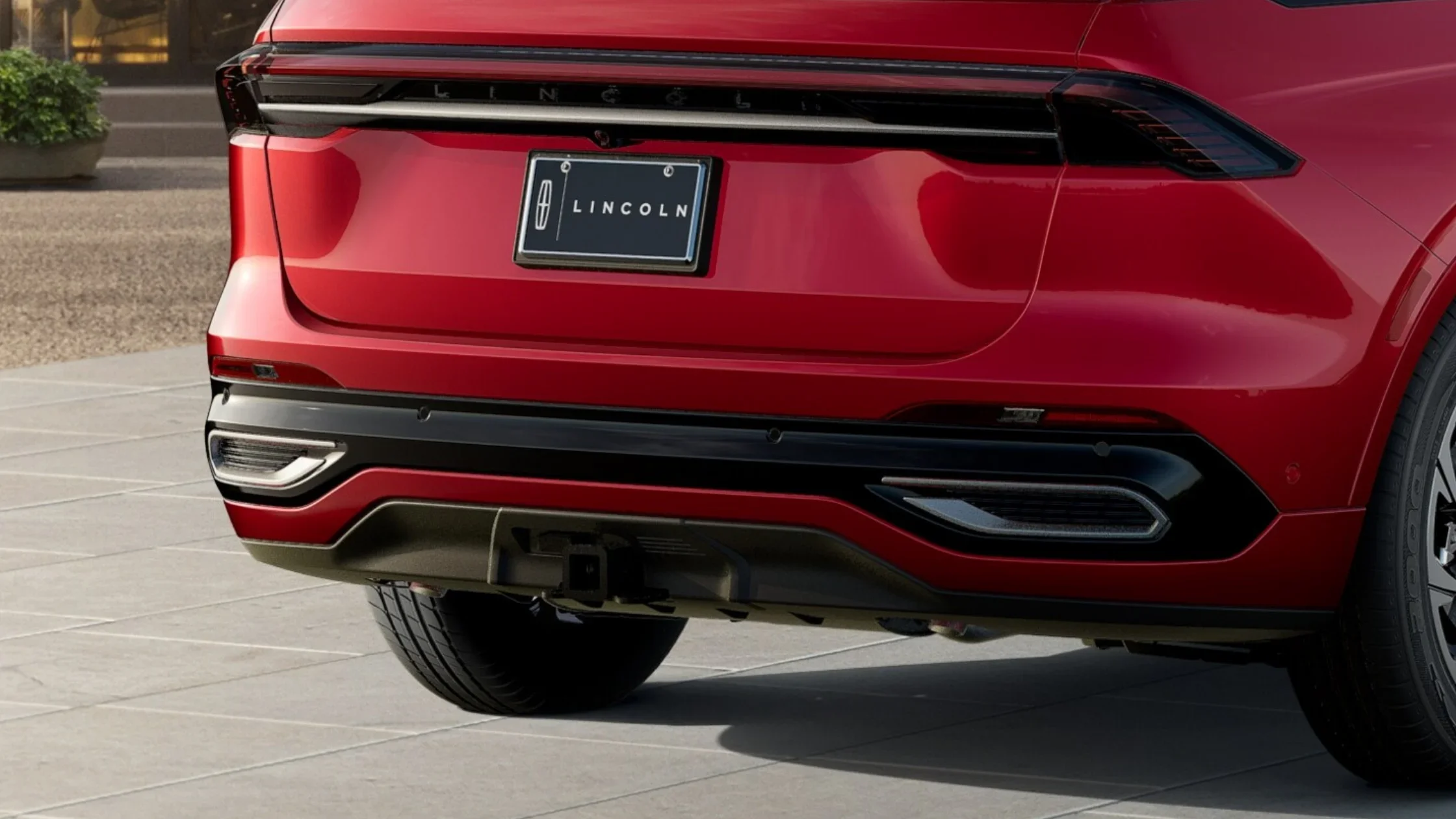 Close-up of the rear end of a red 2025 Lincoln Nautilus® Reserve, featuring sleek LED taillights, dual exhaust outlets, and Lincoln branding.