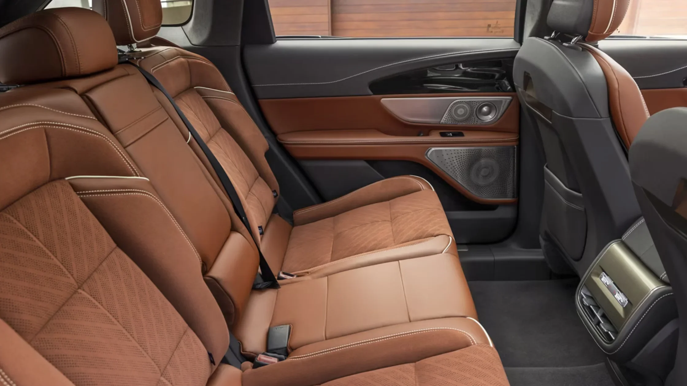 2026 Nautilus® rear seating with premium brown leather upholstery, contrast stitching, and door speaker detail.