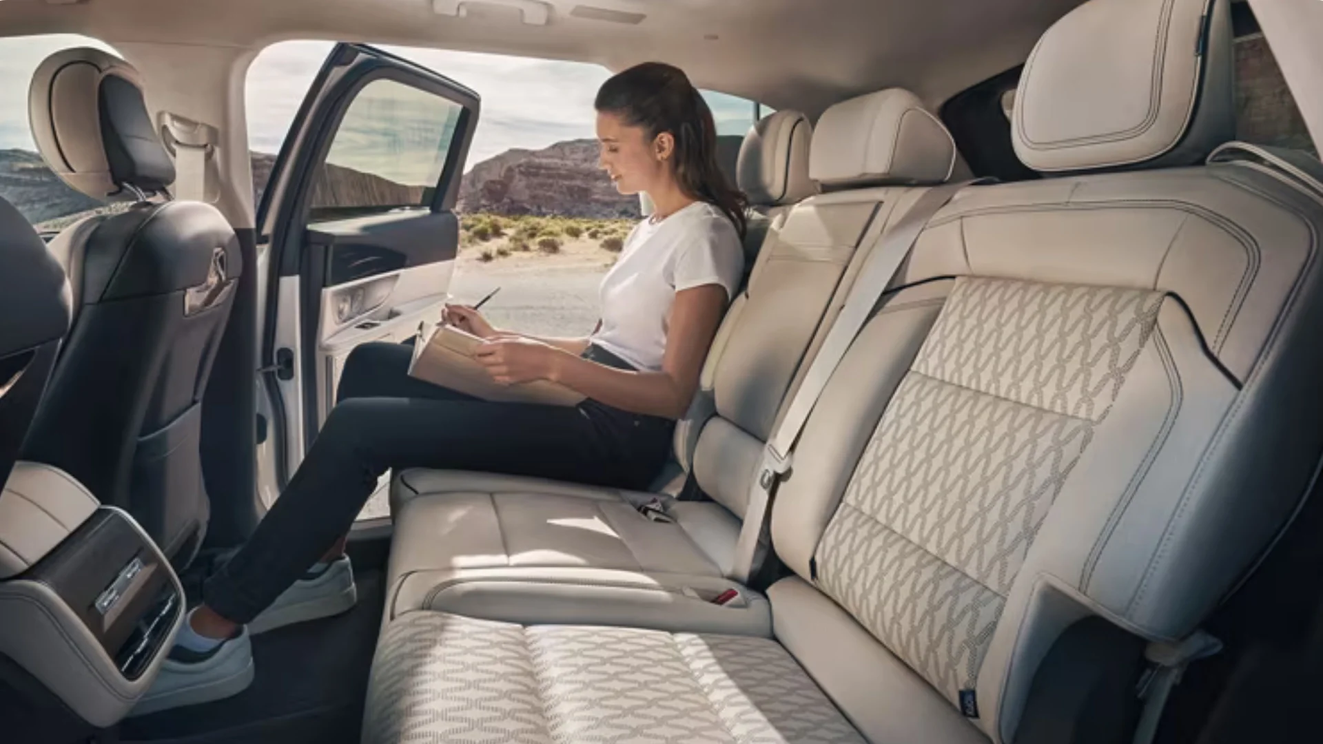 Rear-seat view of a 2025 Black Label Nautilus® with a passenger relaxing in premium light-tone leather seating.