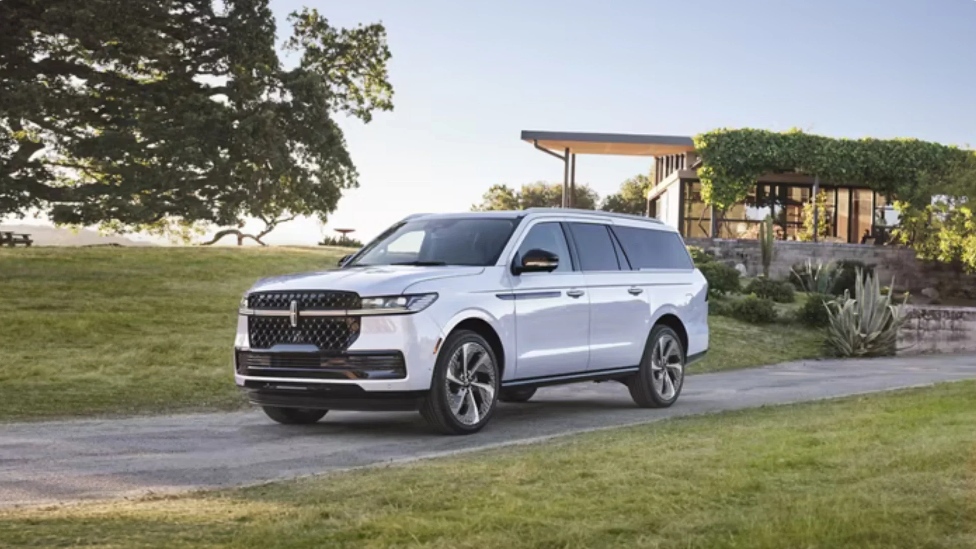 Front-angle view of a 2025 Black Label Navigator® parked on a luxury estate driveway, highlighting its bold grille, refined body lines, and premium presence.