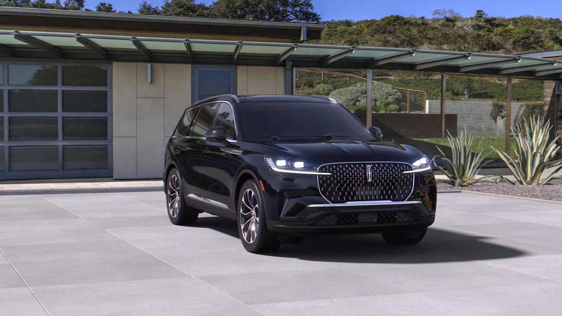 Front view of the 2025 Lincoln Black Label Aviator® in black parked outside a modern home, highlighting its bold grille and luxury design.