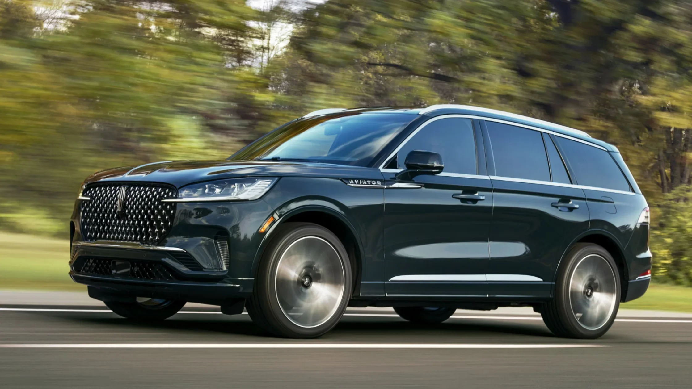2025 Black Label Aviator® side view in motion, dark metallic finish, chrome trim, and bold front grille design.