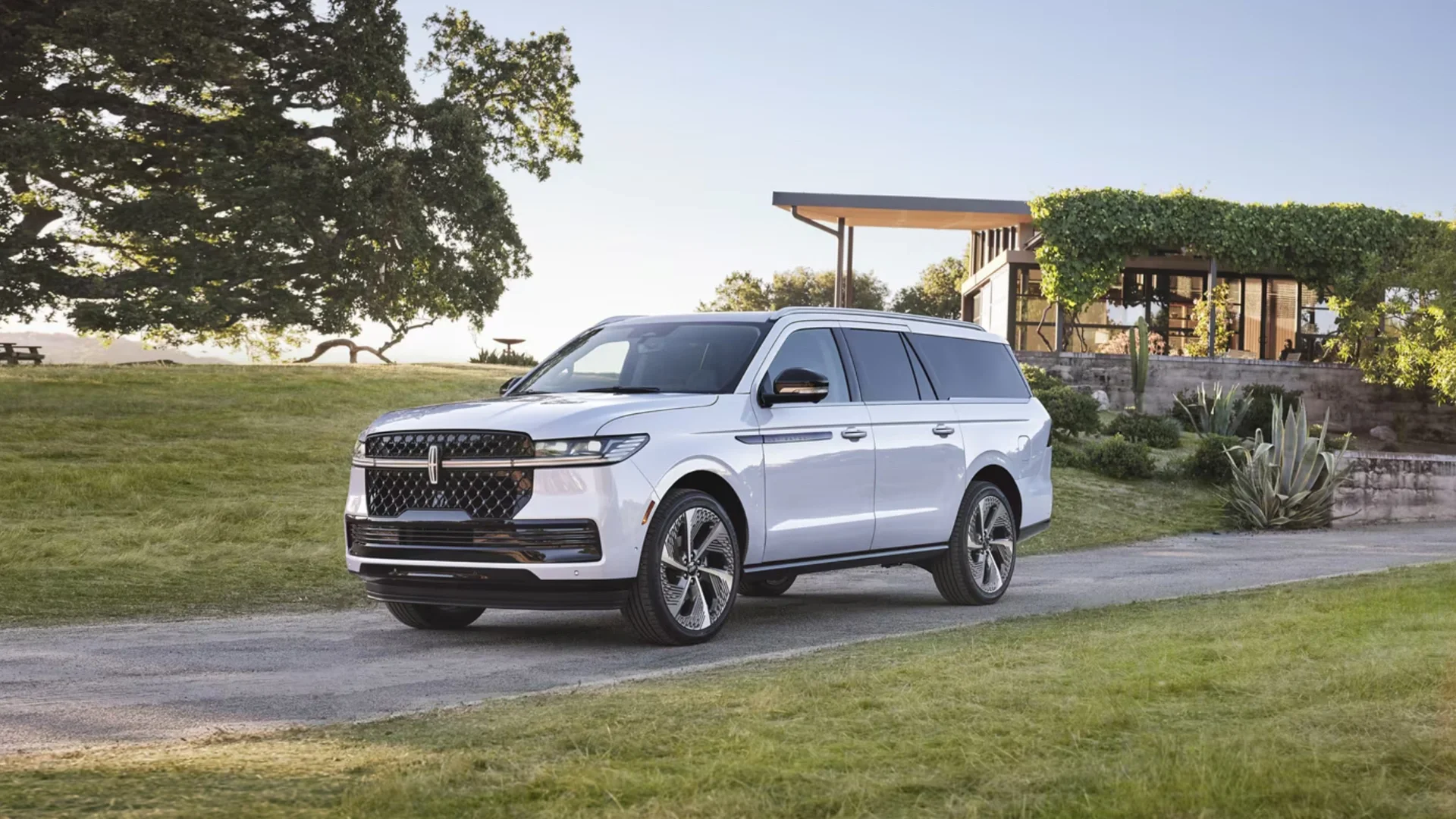 Front three-quarter view of 2025 Lincoln Navigator Black Label parked outside a modern house on green lawn.